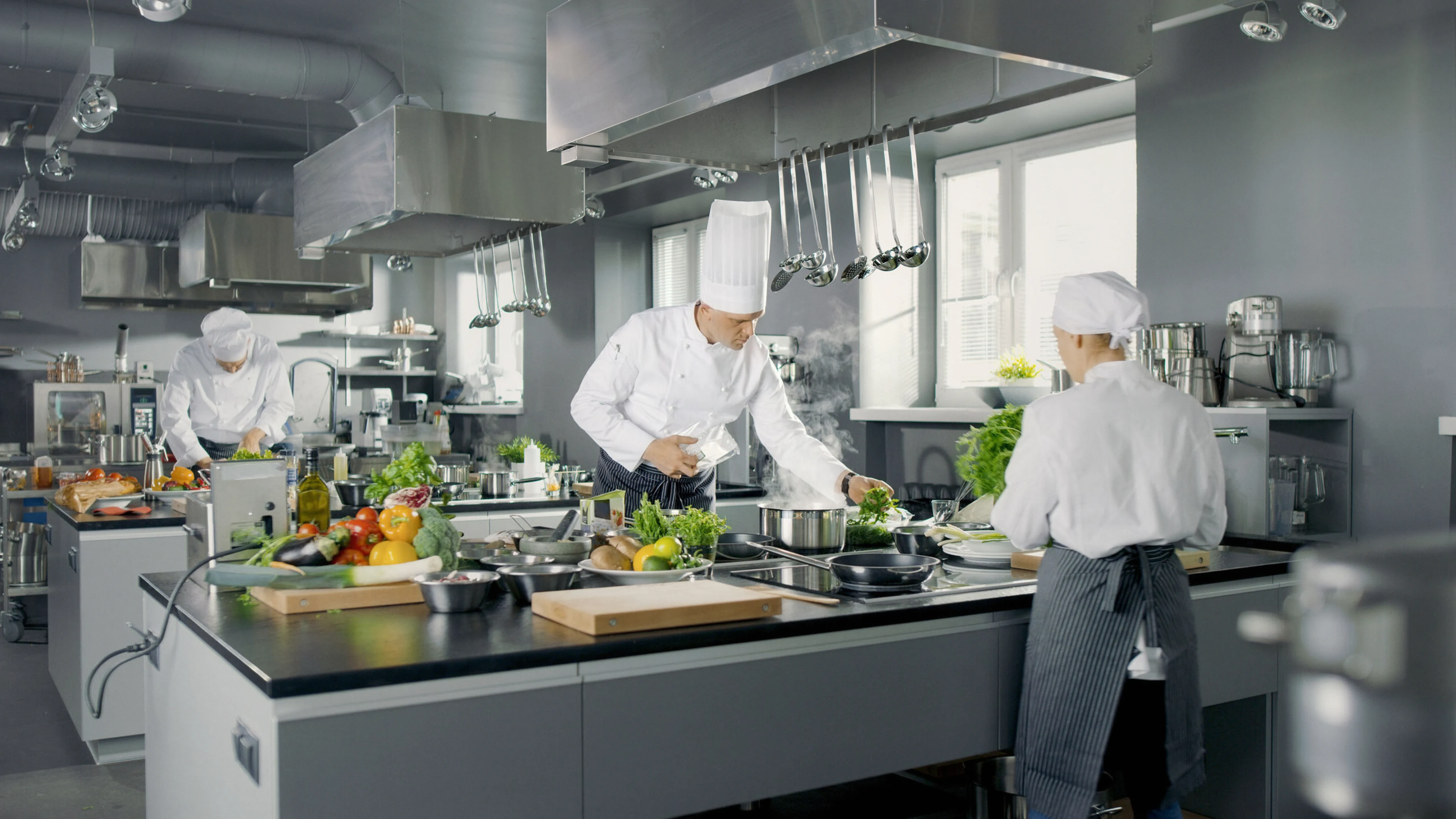 Three chefs preparing food in a commercial kitchen